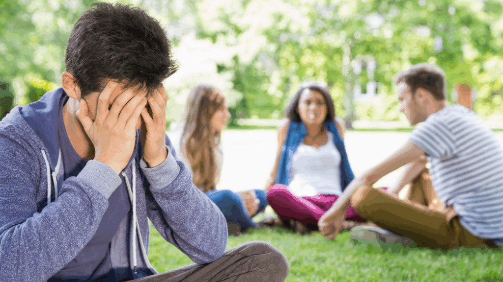 Image d'un jeune homme seul tandis que les autres sont assis avec des amis - 7 façons de dire BEAUCOUP en anglais